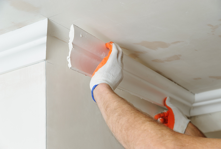 Residential restoration being performed by replacing a white strip of crown molding.
